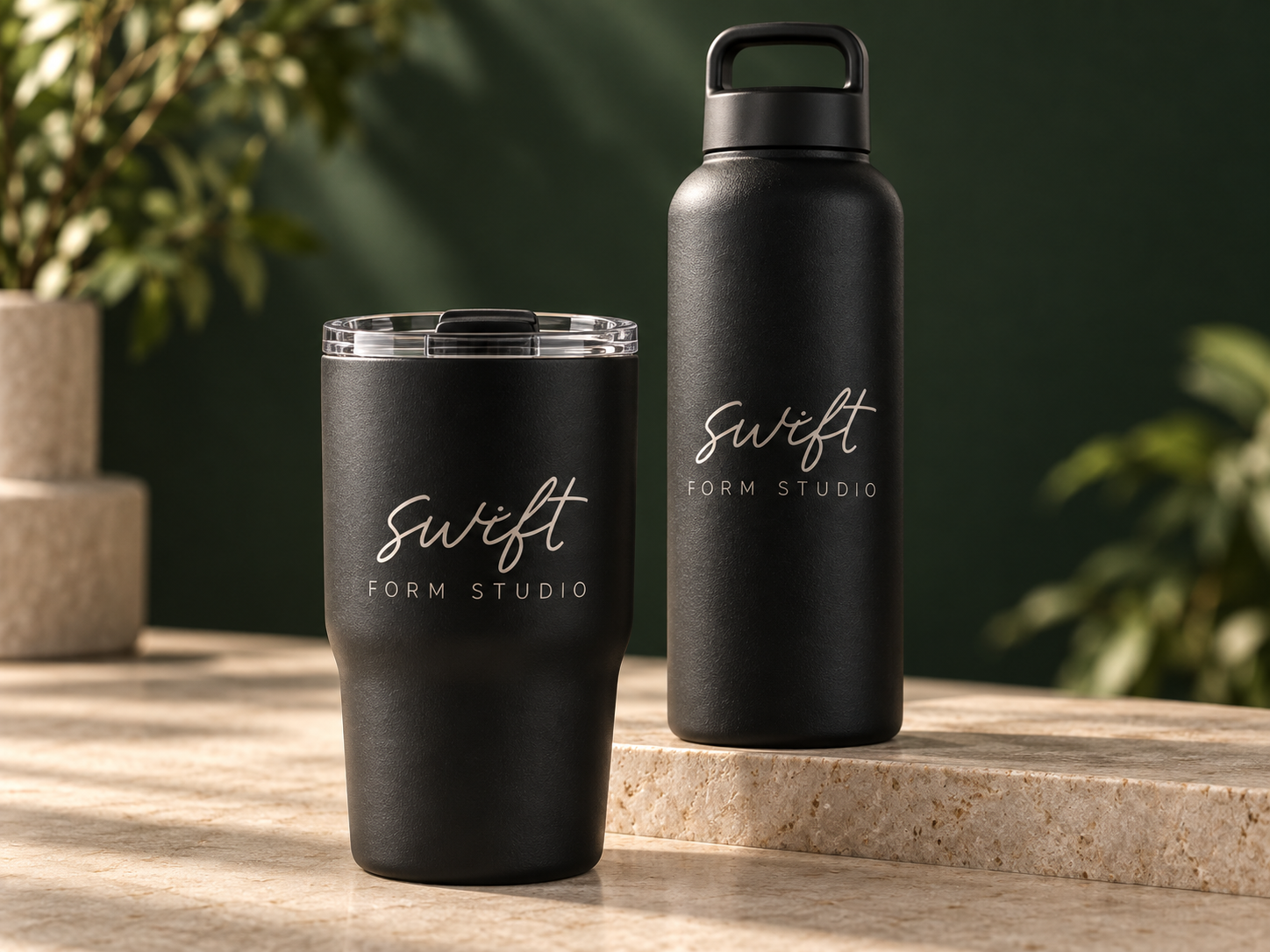 Business logo engraving concepts on a black tumbler and bottle